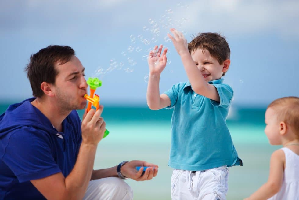 Vacation Travel Innovation Reviews family beach vacation image with parents and children enjoying time by the ocean.